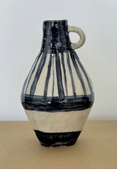 A hand-painted ceramic jug with navy stripes and a curved handle